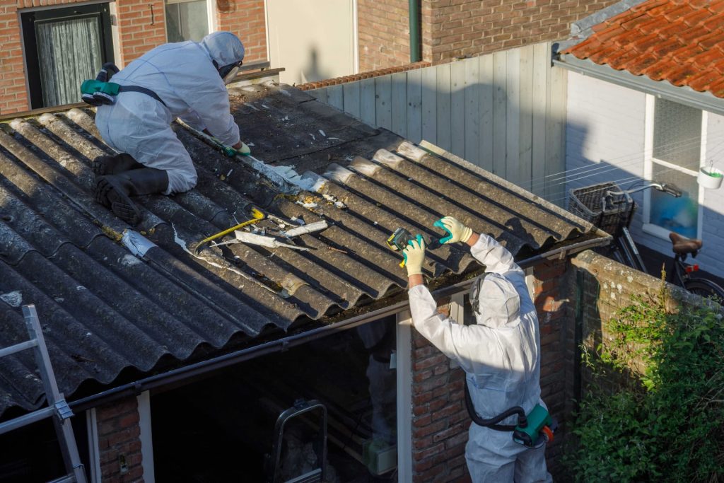 To tømrere som er i gang med nedtagning af asbesttag